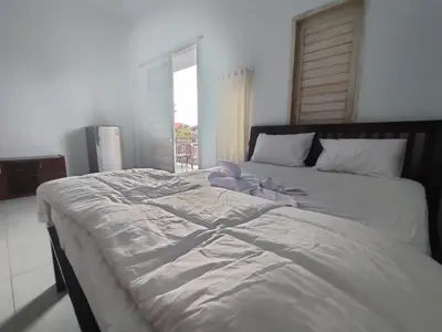 a large white bed in a room with a window at Roy Guest House in Canggu