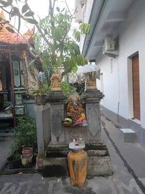 a stone fountain in a courtyard with a tree at Roy Guest House in Canggu
