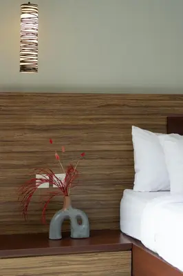 a vase with red flowers on a table next to a bed at Bali Voyage in Seminyak