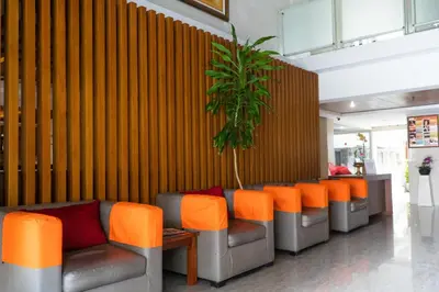 a waiting room with orange chairs and a plant at The Sun Hotel & Spa Legian in Legian