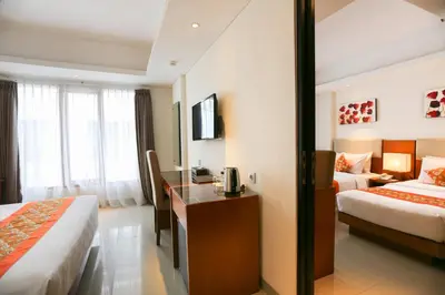 a hotel room with two beds and a desk at The Sun Hotel & Spa Legian in Legian