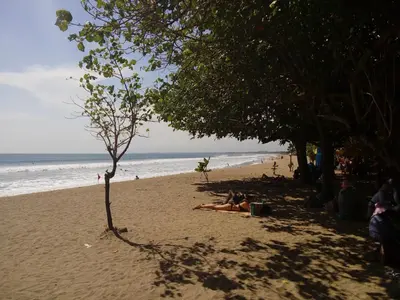 a group of people laying in the sand on the beach at The Sun Hotel & Spa Legian in Legian