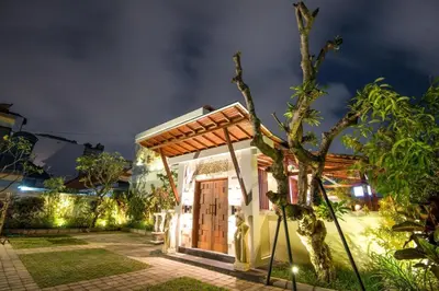 a small house with a wooden door at night at Legian Bisma Suite in Seminyak
