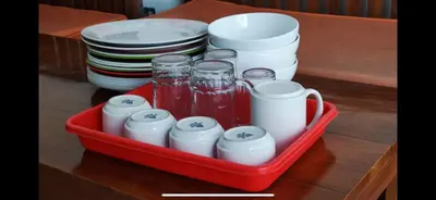a red tray filled with cups and mugs and plates at Cozy Umalas Guesthouse in Kerobokan