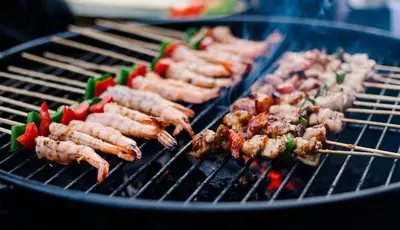 a bunch of skewers cooking on a grill at Villa Sunset by Premier Hospitality Asia in Nusa Dua
