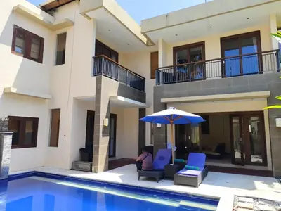 a person sitting under an umbrella next to a house at The Oasis Retreat Seminyak in Seminyak