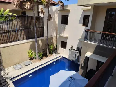 a swimming pool with an umbrella next to a building at The Oasis Retreat Seminyak in Seminyak