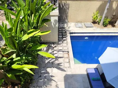 a swimming pool with plants next to a building at The Oasis Retreat Seminyak in Seminyak