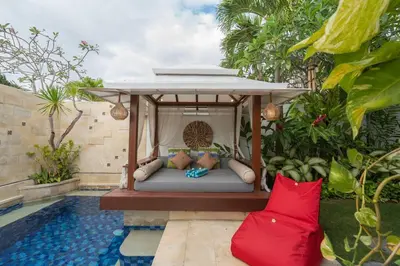 a bed under a gazebo next to a pool at Miracle villa Canggu in Canggu