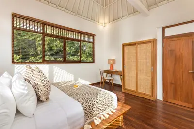 a bedroom with a bed and a desk and windows at Villa Lisabella by Villa Finder in Seminyak