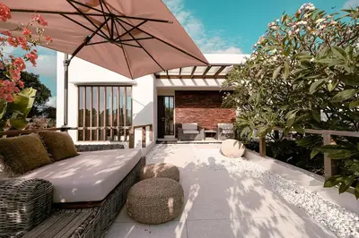a patio with a couch and an umbrella at Sunset Palms Beach Villa in Jimbaran