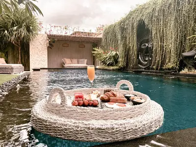 a pool with a table of food in the water at Sunset Palms Beach Villa in Jimbaran