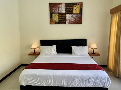 a bedroom with a large white bed with two lamps at Davit Guesthouse Nusa Dua in Nusa Dua