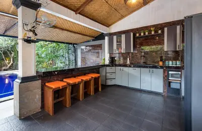 a kitchen with white cabinets and orange cushioned stools at Villa Yati in Seminyak
