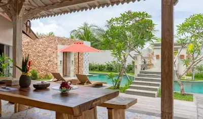 an outdoor patio with a table and chairs and a pool at Vivara Bali Private Pool Villas & Spa Retreat in Jimbaran