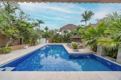 a swimming pool in the backyard of a house with palm trees at Villa Margaretta in Seminyak