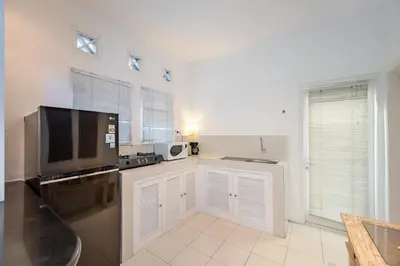 a kitchen with white cabinets and a flat screen tv at Villa Margaretta in Seminyak