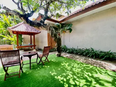 a yard with grass and two chairs and a table at Timaya Villa BEST LOCATION in Legian