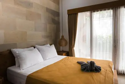 a bedroom with a bed with a large window at Puspa Ayu Villas & Apartments in Kuta