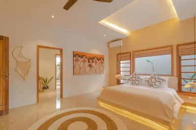 a bedroom with a large white bed and a window at Lamoon Villas Berawa in Canggu