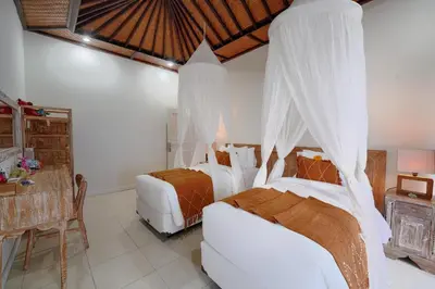a bedroom with two beds and a table at Villa Noni Seminyak in Seminyak
