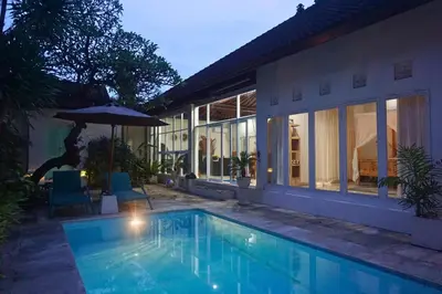 a swimming pool in front of a house with an umbrella at Villa Noni Seminyak in Seminyak