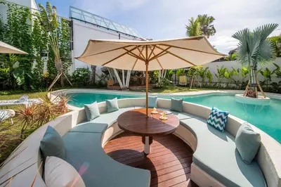a table with an umbrella next to a swimming pool at Villa Annabelle Canggu in Kerobokan