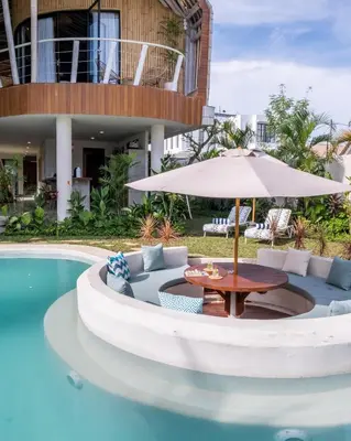 a patio with a table and umbrella next to a pool at Villa Annabelle Canggu in Kerobokan