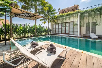 a swimming pool with lounge chairs and a house at Villa Yukiko Canggu in Canggu