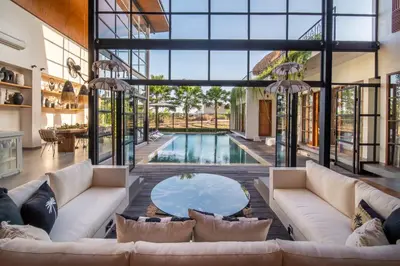 an open living room with a pool and large windows at Villa Yukiko Canggu in Canggu