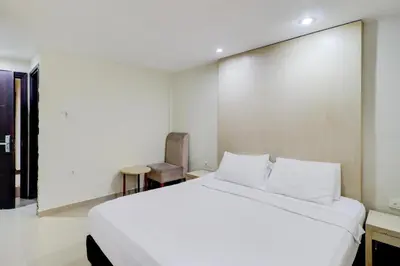 a bedroom with a large white bed and a chair at Collection O Near Bajra Sandi Monumen Formerly Grand Pondok Puri Ayu in Denpasar