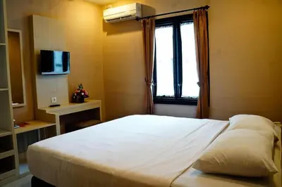 a bedroom with a large white bed with a window at Collection O Near Bajra Sandi Monumen Formerly Grand Pondok Puri Ayu in Denpasar