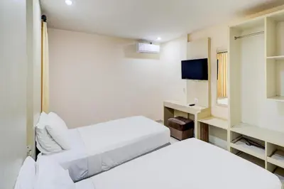a white room with two beds and a television at Collection O Near Bajra Sandi Monumen Formerly Grand Pondok Puri Ayu in Denpasar