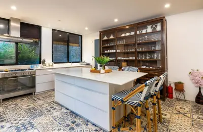 a kitchen with white cabinets and a island with chairs at Villa Iluka by SooBali in Seminyak