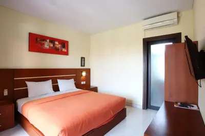 a bedroom with a bed and a flat screen tv at Kondra Premiere Guest House Kuta in Kuta