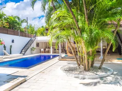 a swimming pool with a palm tree next to a house at Ocean Star 1 in Seminyak