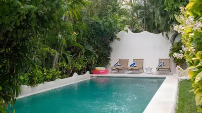 a swimming pool with lounge chairs and trees at Ocean Star 2 in Seminyak