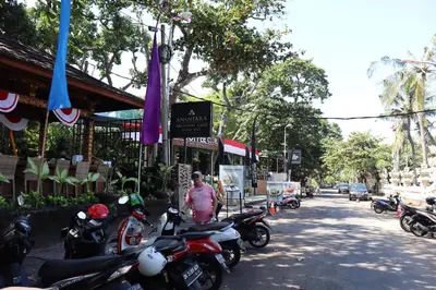 a man standing next to a row of motorcycles on a street at Private Apartment inside Beach Resort Jayakarta in Seminyak
