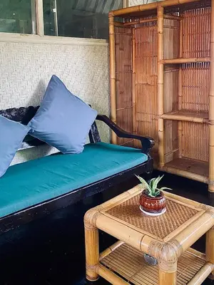 a couch and a table with a potted plant on it at Goestlie Berawa in Canggu