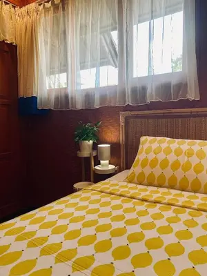 a bedroom with a bed with a yellow comforter and a window at Goestlie Berawa in Canggu