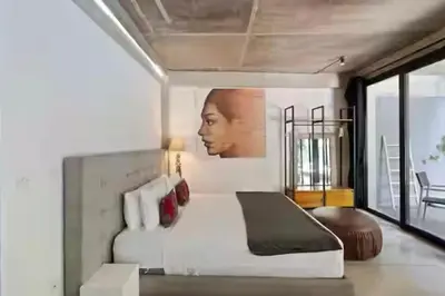 a bedroom with a white bed and a picture of a woman at Modern Apartment with Shared Pool - By the Beach in Seminyak