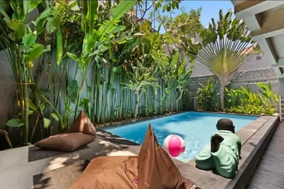 a swimming pool in the middle of a garden at Modern Apartment with Shared Pool - By the Beach in Seminyak