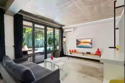 a living room with a couch and a large window at Modern Apartment with Shared Pool - By the Beach in Seminyak