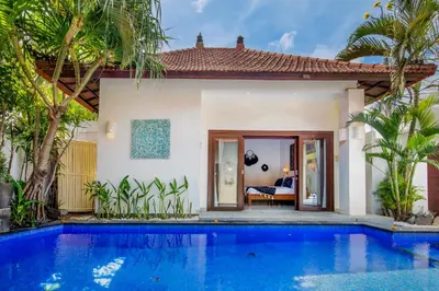 a villa with a swimming pool in front of a house at Villa Joyosa in Seminyak