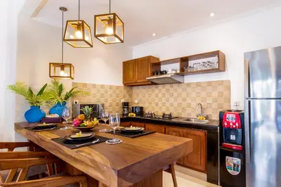 a kitchen with a wooden table and a refrigerator at Villa Joyosa in Seminyak