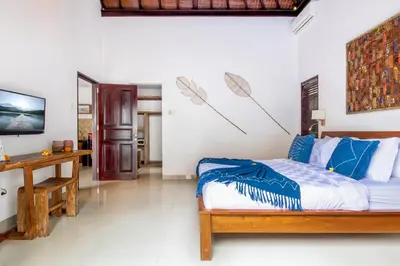 a bedroom with a bed and a desk in a room at Villa Joyosa in Seminyak
