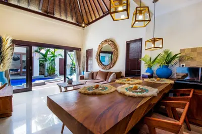 a dining room with a wooden table and a living room at Villa Joyosa in Seminyak