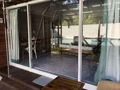 a screened in porch with a view of a pool at Bali WOW! Bungalows, Nusa Dua Benoa in Nusa Dua