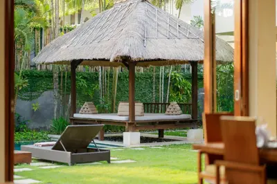 a bed with a straw umbrella and a laptop at The Suar Seminyak by Nakula in Seminyak