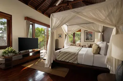 a bedroom with a canopy bed with a television at The Suar Seminyak by Nakula in Seminyak